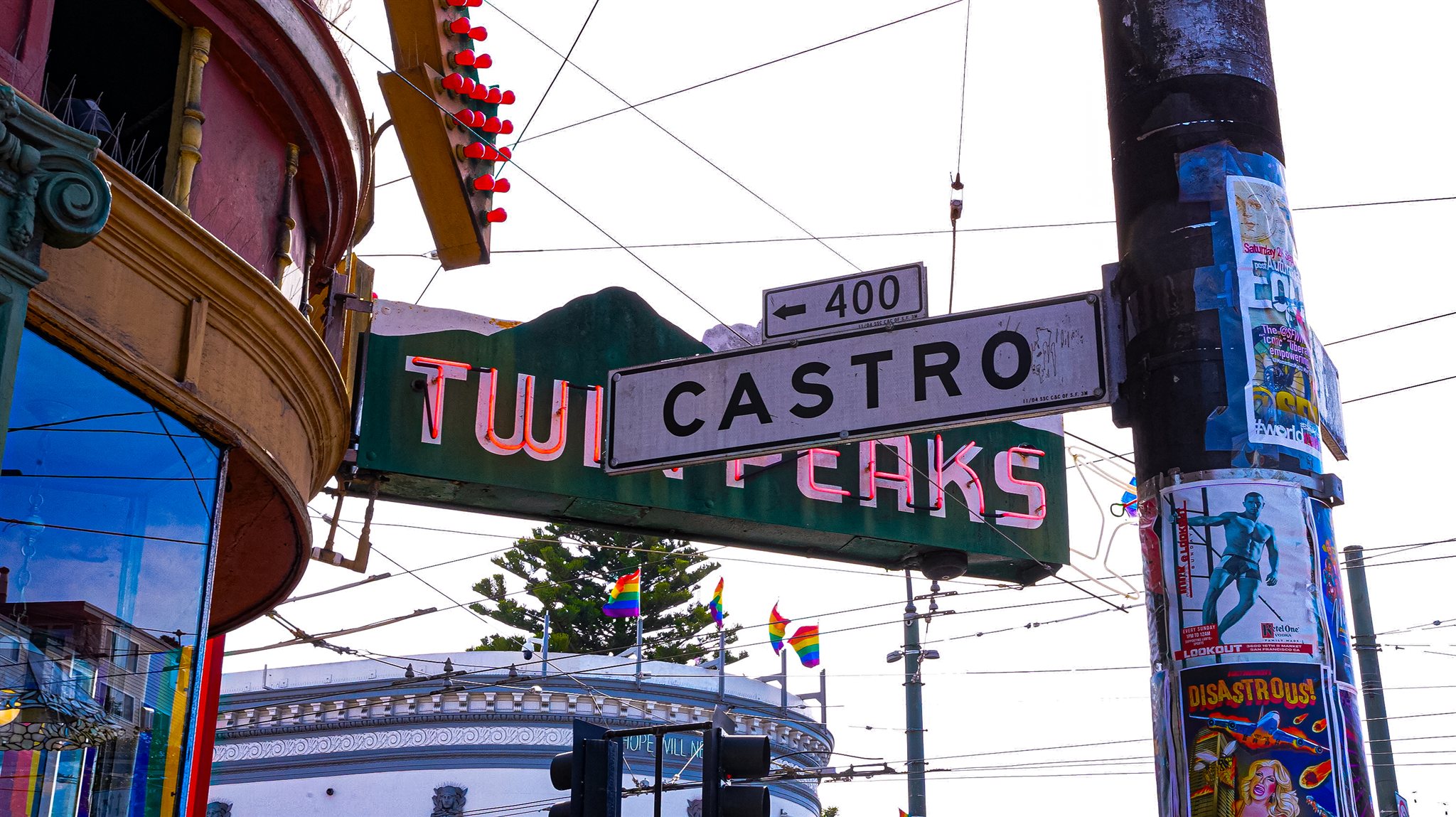Castro street sign and Twin Peaks neon beside a curved storefront