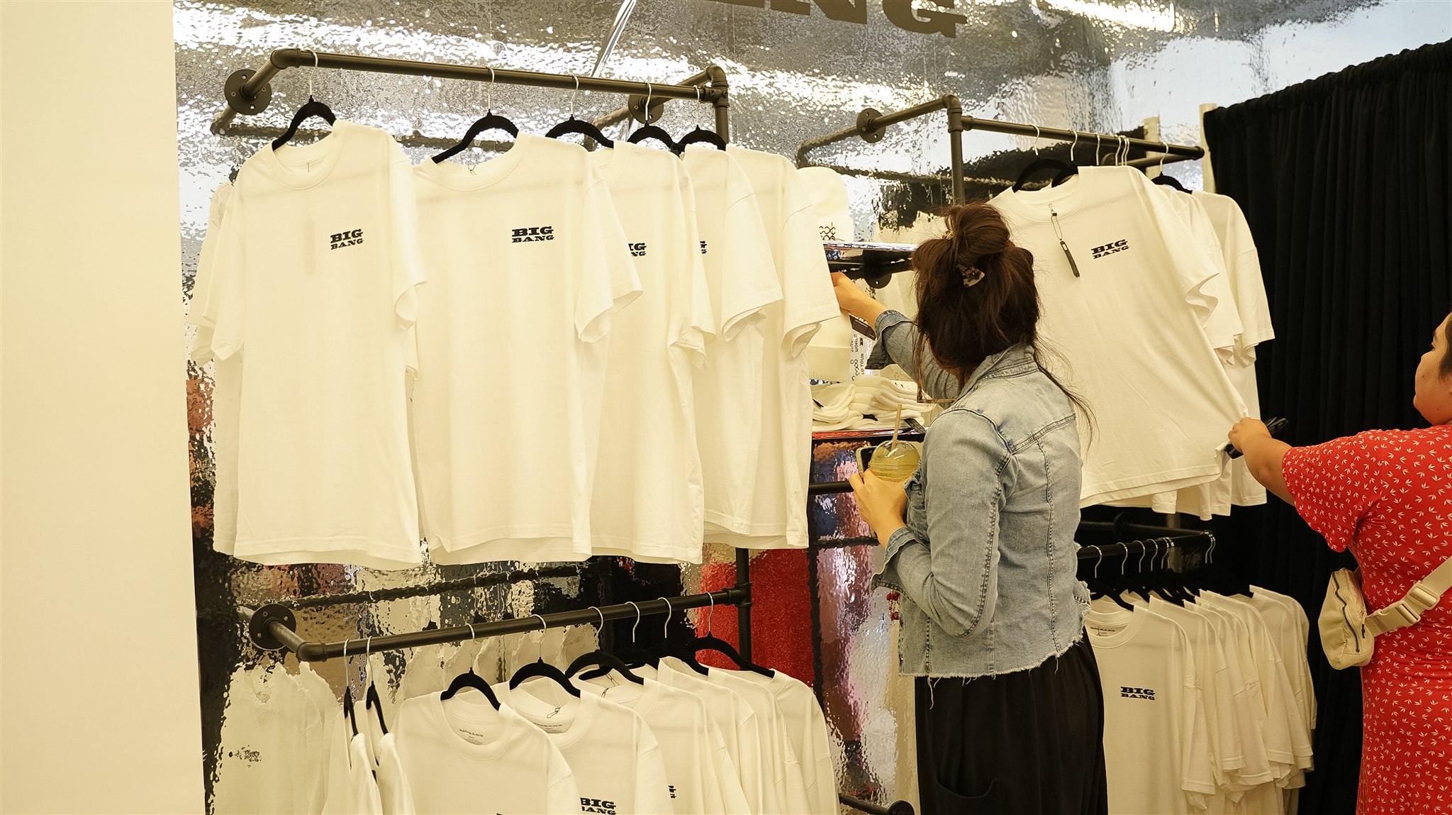Attendees browsing BIGBANG shirts at a merchandise display